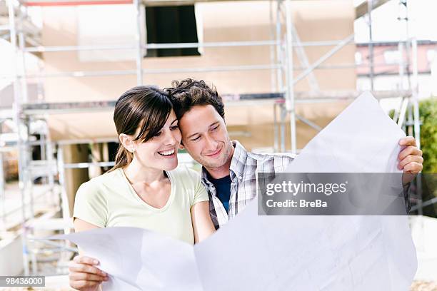 portrait of couple in front their new home with plan - bavarian man in front of house stockfoto's en -beelden
