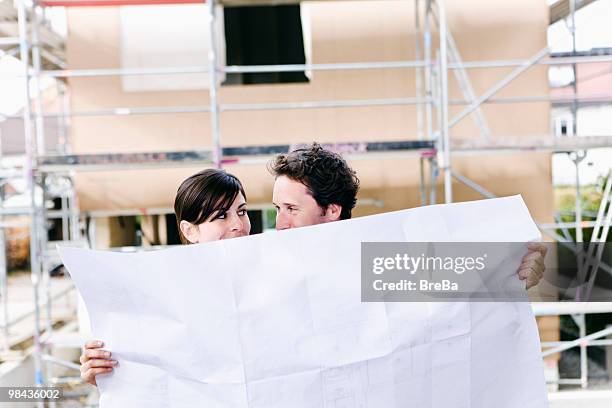 portrait of couple in front their new home with plan - bavarian man in front of house stockfoto's en -beelden