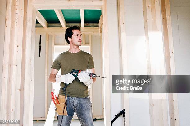 full body portrait of young man standing in door of house under construction - man standing full body photos et images de collection