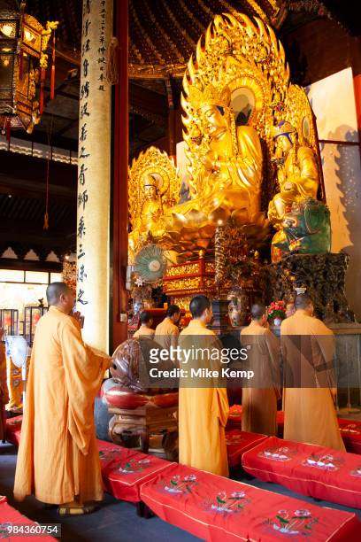 Buddhist monks in ochre yellow robes during one of their daily prayer sessions at Longhua Temple in the south of Shanghai, China. This is a working...
