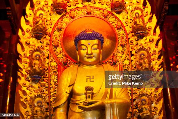 Golden Buddhist statues and interior at Longhua Temple in the south of Shanghai, China. This is a working temple where public come to burn incense,...
