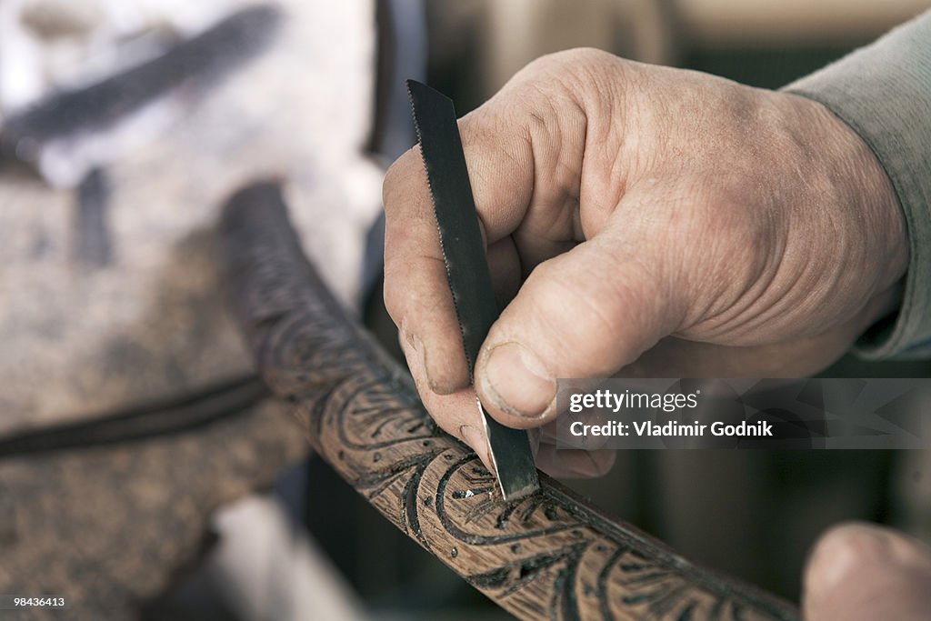 Close-up of carpenter carving piece of wood