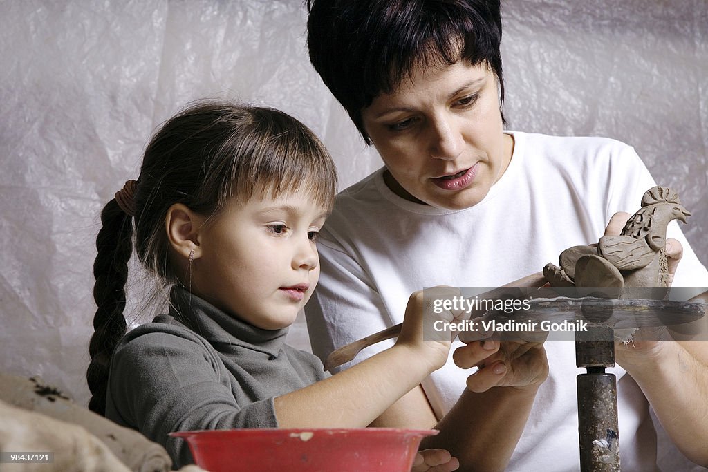 Mother and daughter forming sculpture out of clay together