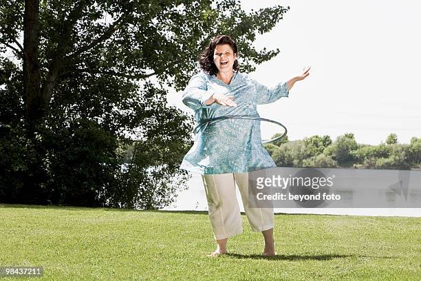 full body portrait of overweight woman doing hula hoop in the park - hula hoop ストックフォトと画像
