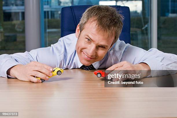 portrait of businessman playing with toy cars - statussymbol bildbanksfoton och bilder