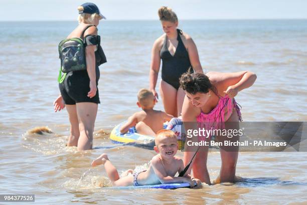 Katie Roberts, pulls along Ricardo Johnson from Newport on a bodyboard in the sea at Barry Island, Vale of Glamorgan, Wales, as temperatures are...