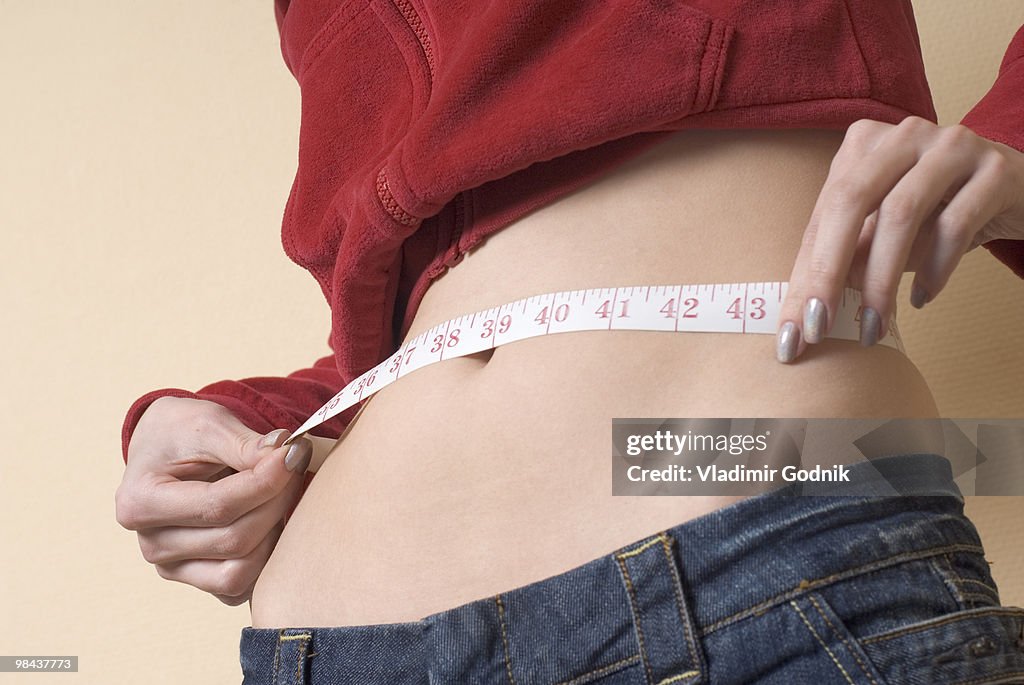 Young woman measuring her waistline