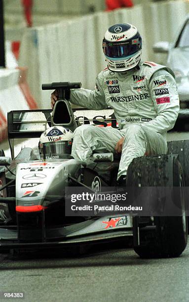 Mika Hakkinen of McLaren and Finland rides back to the paddock on his team mate David Coulthards car after an engine blow during the Spanish Formula...