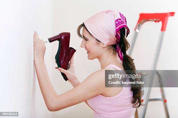 tennage girl doing decoration work using shoe as hammer - fotohandy stock pictures, royalty-free photos & images