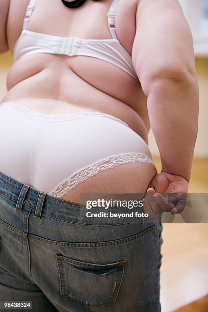 rear view of overweight woman trying to put on jeans trousers - studiofoto stock pictures, royalty-free photos & images