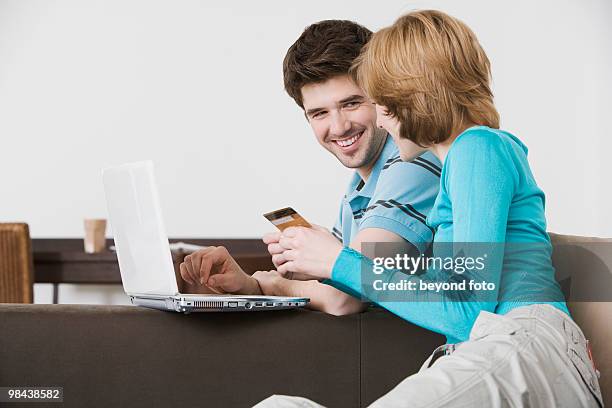 young couple in front of laptop computer with credit card - bavarian man in front of house stockfoto's en -beelden