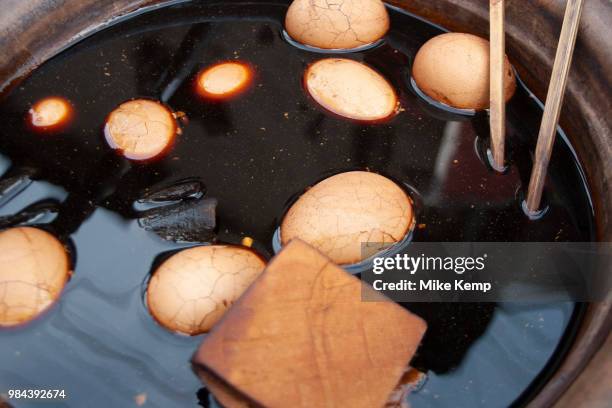 Eggs and tofu float in a bowl of warmed Chinese soy sauce in Shanghai, China. A very common street snack, these can be bought all over Shanghai and...
