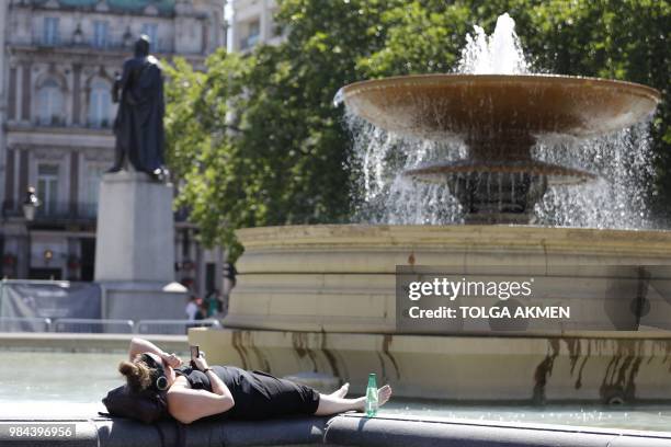 Members of the public enjoy the warm weather by the fountains in Trafalgar square in central London on June 26, 2018. Britain has been enjoying the...
