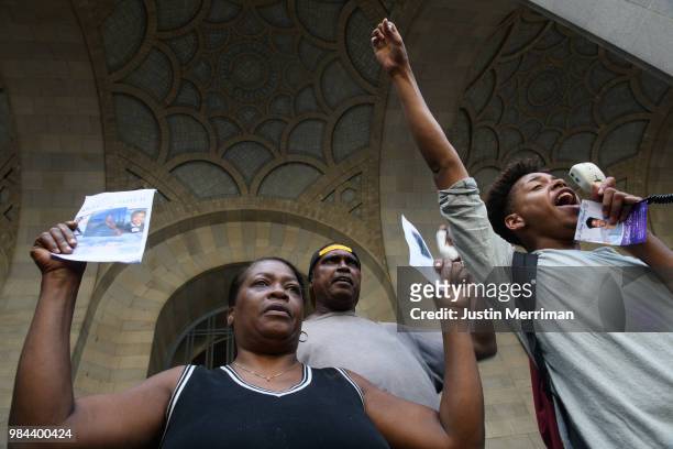 Christian Carter of East Liberty speaks to a crowd as Carmen Ashley, the great aunt of Antwon Rose II, holds the memorial card from Rose's funeral...