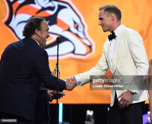 Actor Jim Belushi presents Pekka Rinne of the Nashville Predators with the Vezina Trophy, given to the top goaltender, during the 2018 NHL Awards...