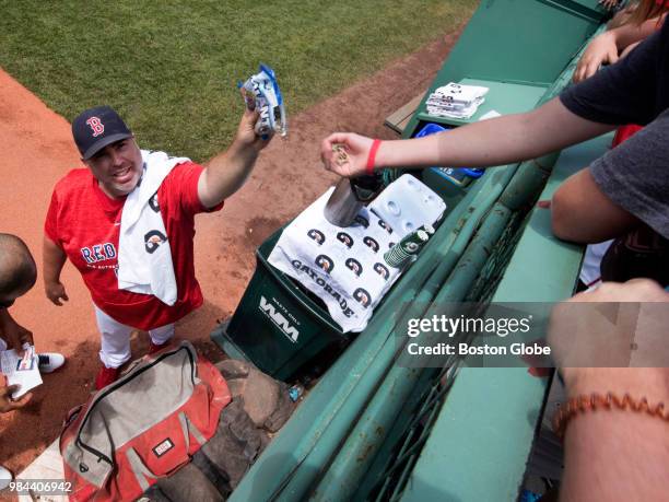 Craig Bjornson, Boston Red Sox bullpen coach, gives sunflower seeds to fans in the bleachers before the start of a game at Fenway Park in Boston on...