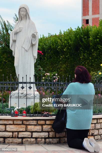 Catholic pilgrim woman prays in front of the satue of holy mother Mary, in the southern Bosnian village of Medjugorje, on June 26, 2018. - To...