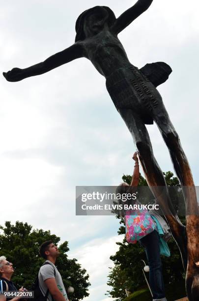 Catholic pilgrims gather to touch the statue of Jesus Christ near the Franciscan church of St. Jacob in the southern Bosnian village of Medjugorje,...