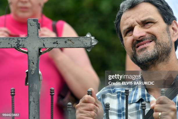 Catholic pilgrim prays in front of the crucifix near the statue of holy mother Mary, in the southern Bosnian village of Medjugorje, on June 26, 2018....