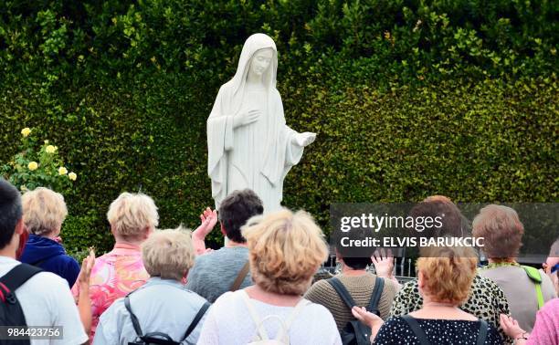 Catholic pilgrims pray in front of the satue of holy mother Mary, in the southern Bosnian village of Medjugorje, on June 26, 2018. - To believers,...