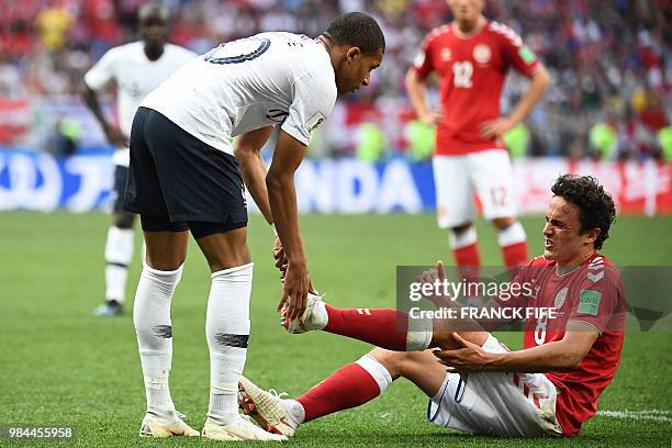 France's forward Kylian Mbappe checks on Denmark's midfielder Thomas Delaney after falling down during the Russia 2018 World Cup Group C football...