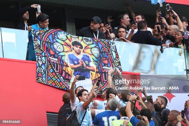 Argentina legend Diego Maradona holds a flag of himself as fans react prior to the 2018 FIFA World Cup Russia group D match between Nigeria and...