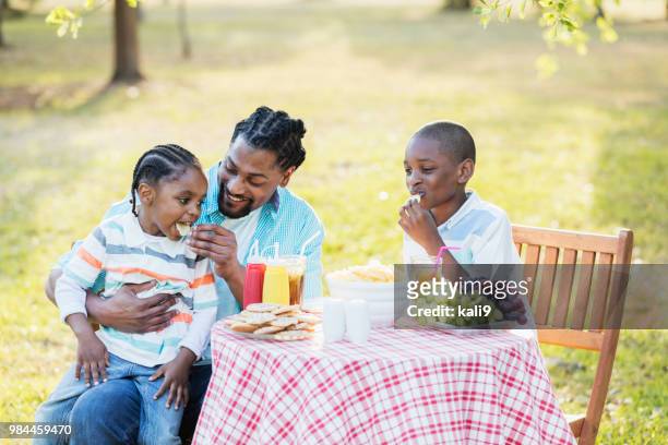 father, two boys at cookout, eating potato chips - family eating potato chips imagens e fotografias de stock