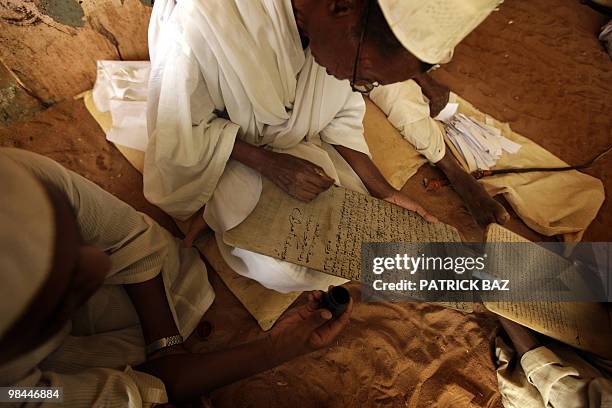 Sudanese Sufi teacher writes on a wooden board or Lawha as his student holds the ink for him at the Qadiriya Badiriya Sufi mosque in the village of...