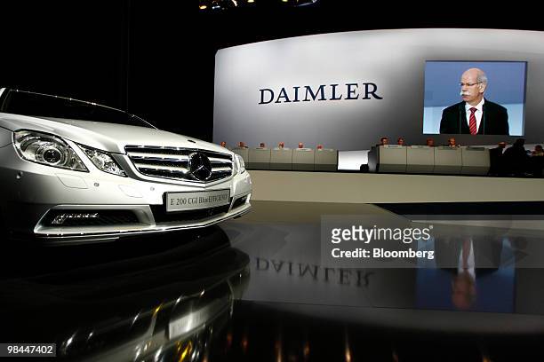 Dieter Zetsche, chief executive officer of Daimler AG, speaks on a large screen behind a a Mercedes E200 CGI Blue efficiency automobile at the...