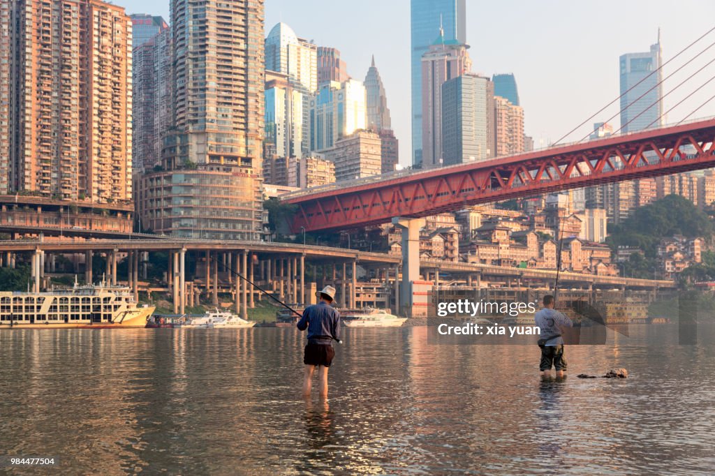 People fishing in the Jialing River against Chongqing skyline,China