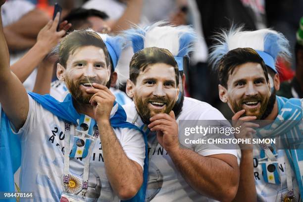 Argentina supporters wearing masks bearing the face of Argentina's forward Lionel Messi pose ahead of the Russia 2018 World Cup Group D football...