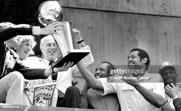 The Larry O'Brien Championship Trophy is handed past Boston Celtics general manager Red Auerbach to player M.L. Carr during the Celtics' NBA...