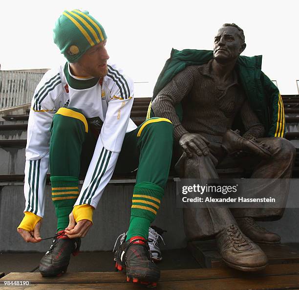 Matthew Booth of the South African national football team sits next to a statue of Adi Dassler, founder of adidas company prior to training session...