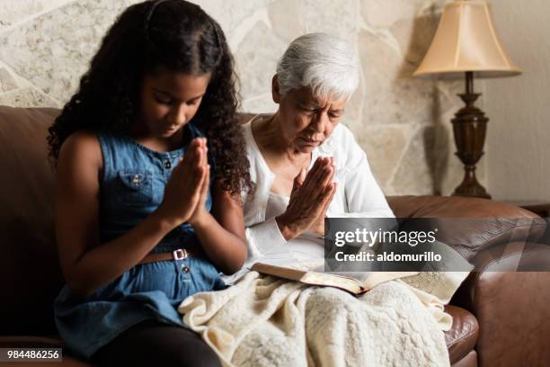 Ältere Frau und Mädchen auf dem Sofa sitzen und beten