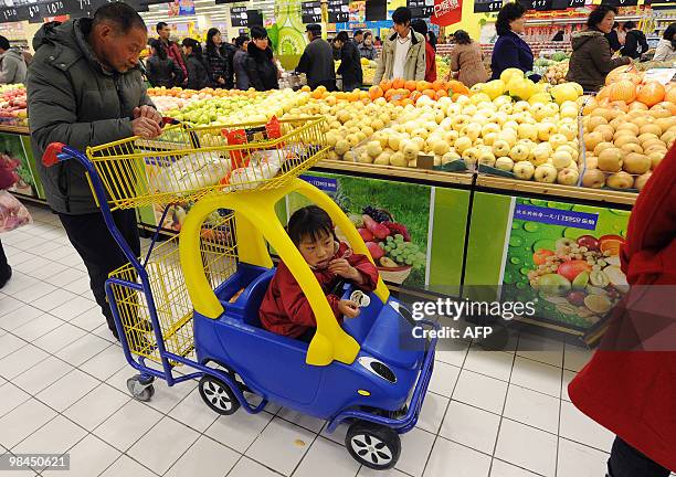 Chinese man pushes a child in a cart while shopping at a supermarket in Hefei, central China's Anhui province on April 13, 2010. The Asian...