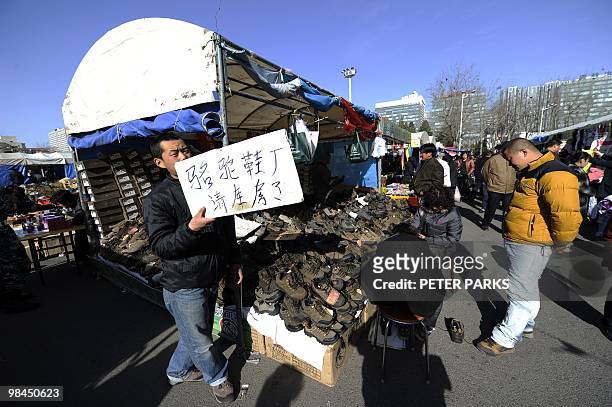 Vendor advertises shoes he sells at an outdoor market in Beijing on April 13, 2010. The Asian Development Bank urged China to step up efforts to...