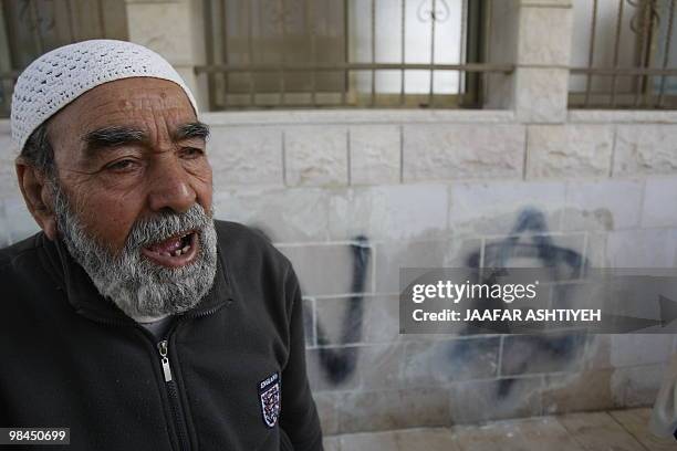 Palestinian man stands in front of a star of David and Hebrew graffiti that was allegedly spray-painted by Jewish settlers on the wall of a mosque in...