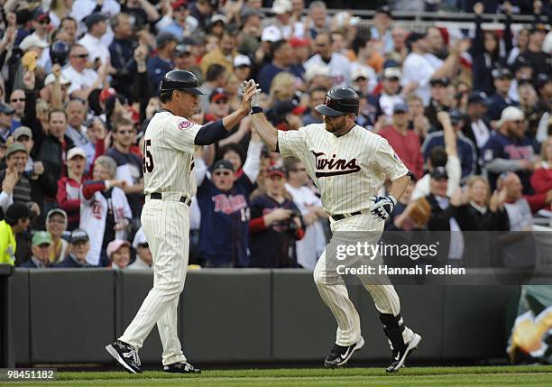 Third base coach Scott Ullger and Jason Kubel of the Minnesota Twins celebrate Kubel hitting the first home run at Target Field in the seventh inning...