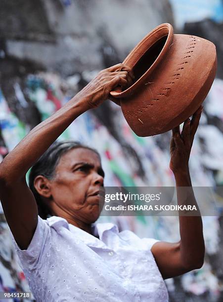 Sri Lankan vendor inspects an earthenware pot she is selling at the roadside in Colombo on April 12, 2010. Sinhala Tamil New Year celebrations will...