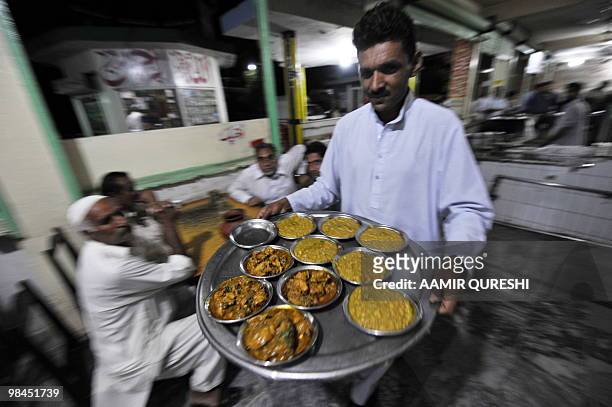 Waiter carries food to be served to customers at the popular Mian Ji restaurant, located at GT Road in Lala Musa, late on April 13, 2010. Mian Ji,...