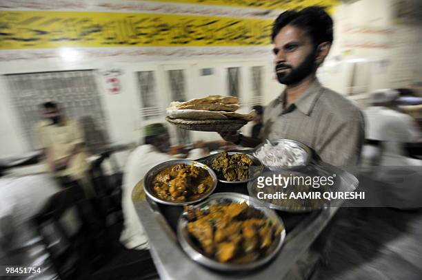 Pakistani waiter carries food to customers at a famous Mian Ji restaurant located at Lala Musa GT Road late on April 13, 2010. Mian Ji is located at...