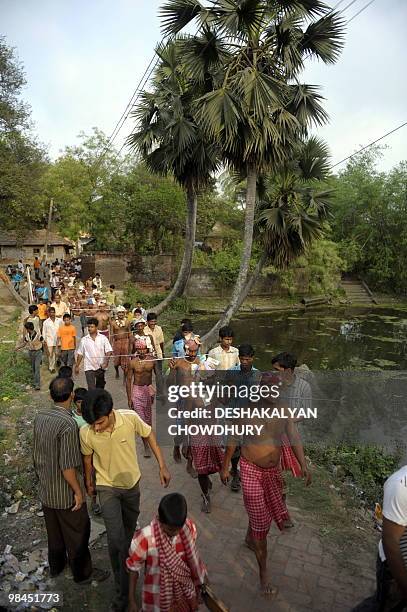 Indian Hindu devotees walk with their tongues pierced with metal rods during the ritual of Shiva Gajan at a village in Bainan, some 80 kms south of...