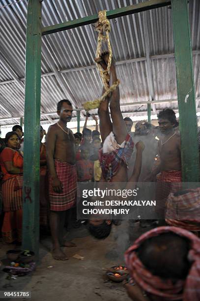 An Indian Hindu devotee hangs himself upside down over a fire during the ritual of Shiva Gajan at a village in Bainan, some 80 kms south of Kolkata,...