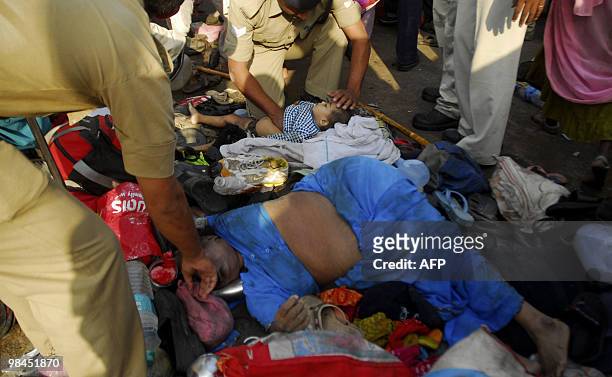 Indian policemen try to help a child and a woman after they were caught in a stampede at the Kumbh Mela festival in Haridwar on April 14, 2010. In...