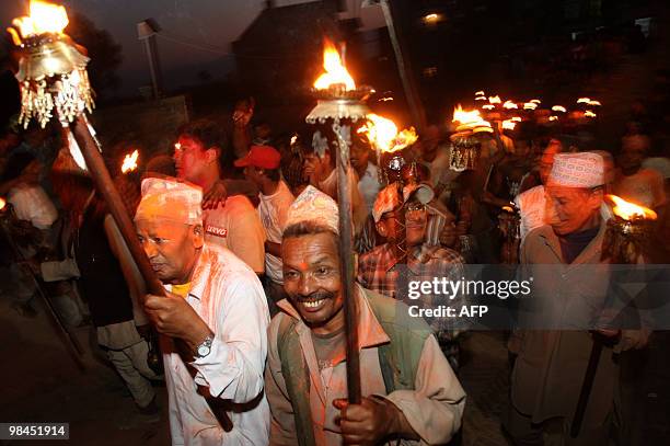 Nepalese devotees walk with flaming torches and colour smeared onto their faces as they gather to take part in Bisket Jatra, a festival held in...