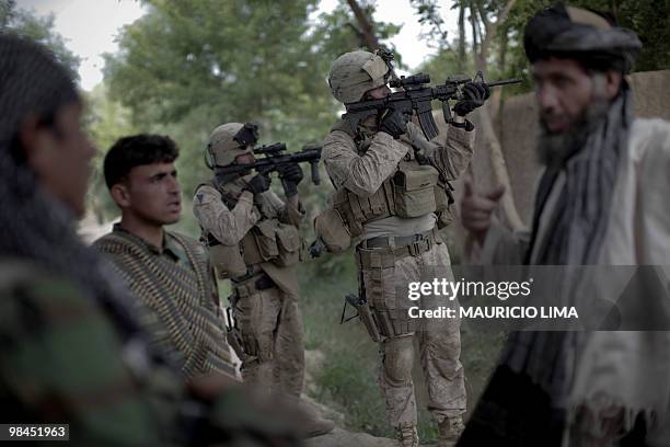 Marines from India Company, 3rd Battalion, 6th Marines, aim their M4 rifle while an Afghan farmer answers questions from Afghan National Army...