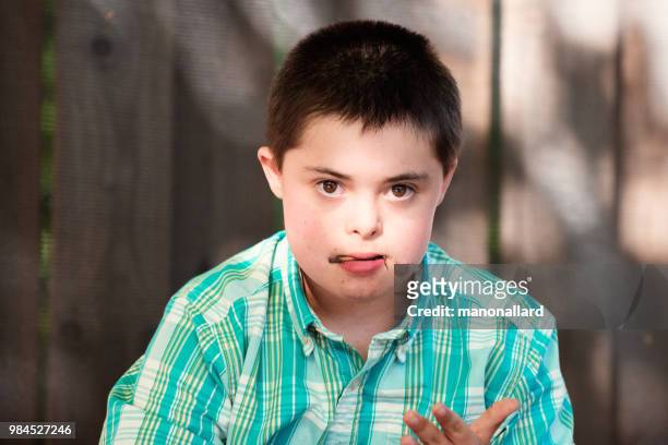 portrait of an authentic boy of 12 years old with autism and down syndrome in daily lives - portrait looking down stock pictures, royalty-free photos & images