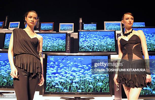 Models stand beside Toshiba's new high-definition Liquid Crystal Display television series, "LED Regza" during the press preview in Tokyo on April...