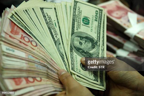 Bank clerk counts US dollars and Chinese yuan at a bank in Hefei, east China's Anhui province on April 13, 2010. The impact of a stronger currency on...