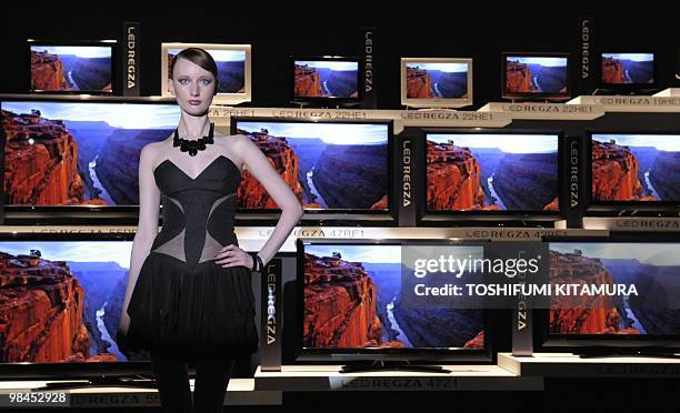 Model stands beside Toshiba's new high-definition Liquid Crystal Display television series, "LED Regza" during the press preview in Tokyo on April...